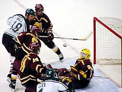 FSU goalie Mike Brown does all he can to keep the puck out of the night, with Adam Hall and Jon-Michael Liles bearing down.