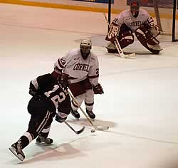 Cornell's Jeremy Downs blocks a shot by Crimson Kenny Turano.