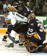 Sioux forward Rory McMahon is checked by Canisius defenseman Brandon Irish-Baker as goalie Bryan Worosz covers up on a shot. McMahon had a goal and an assist in North Dakota's 6-0 win.