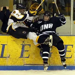 UNH's Brian Pouliot (r.) checks Merrimack's Rob LaLonde into the boards (photos: Josh Gibney).