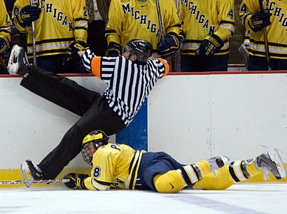 Michigan's Aaron Palushaj submarines referee Chip McDonald (photo: Melissa Wade).