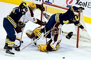 Michigan's Aaron Palushaj goes flying over Minnesota netminder Jeff Frazee, who stopped 44 shots (photo: Melissa Wade).