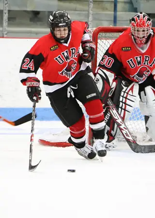 River Falls' Lauren Conrad carries the puck up the ice as Falcon goaltender Cassi Campbell looks on. (photo credit: Will Costello)