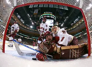 Harvard's Daniel Moriarty and BC's John Muse in the net along with the puck, off the stick of HU's Pier-Olivier Michaud.